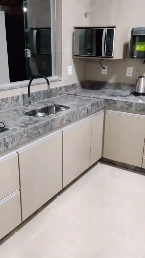 Cozinha em L com armários bege e bancada de granito