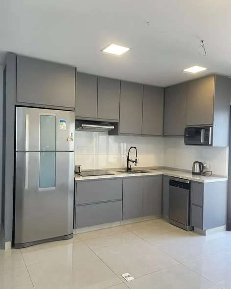 Cozinha planejada cinza com armários até o teto, geladeira inox e cooktop