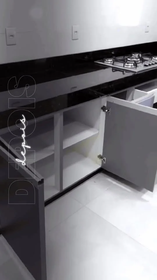 Armário de cozinha branco com bancada preta e cooktop, porta aberta mostrando o interior
