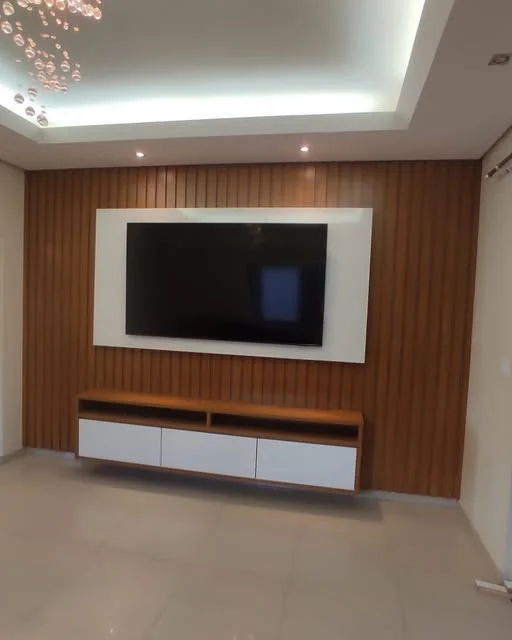 Painel de TV ripado amadeirado com moldura branca e rack suspenso, sob sanca iluminada